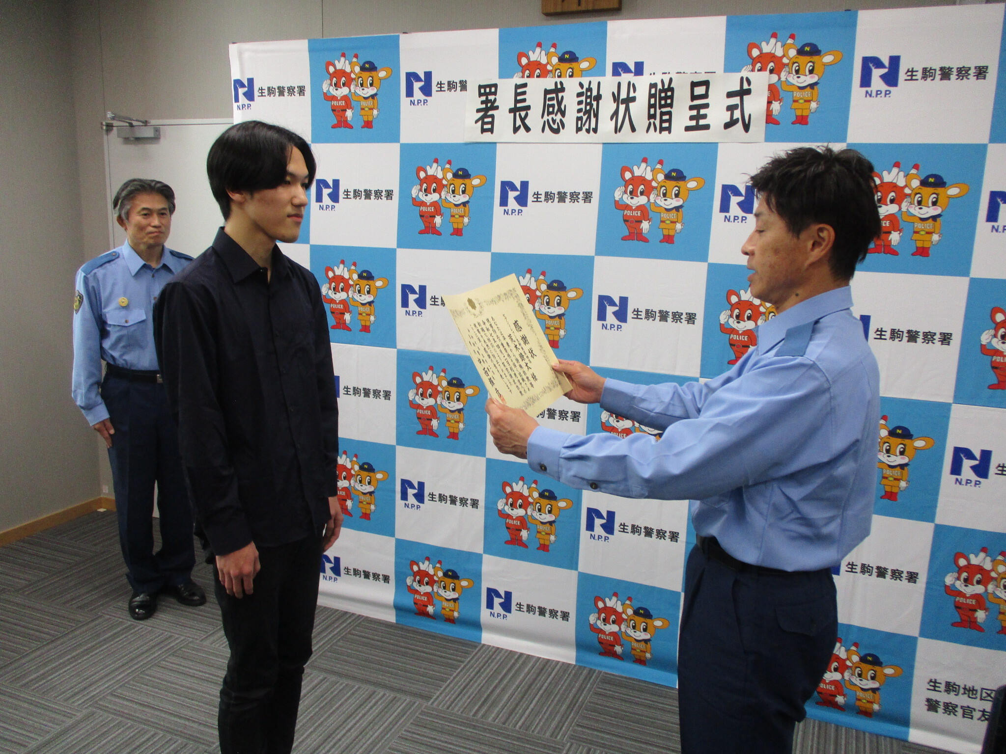 コンビニエンスストア店員が生駒警察署長から感謝状を受け取る様子
