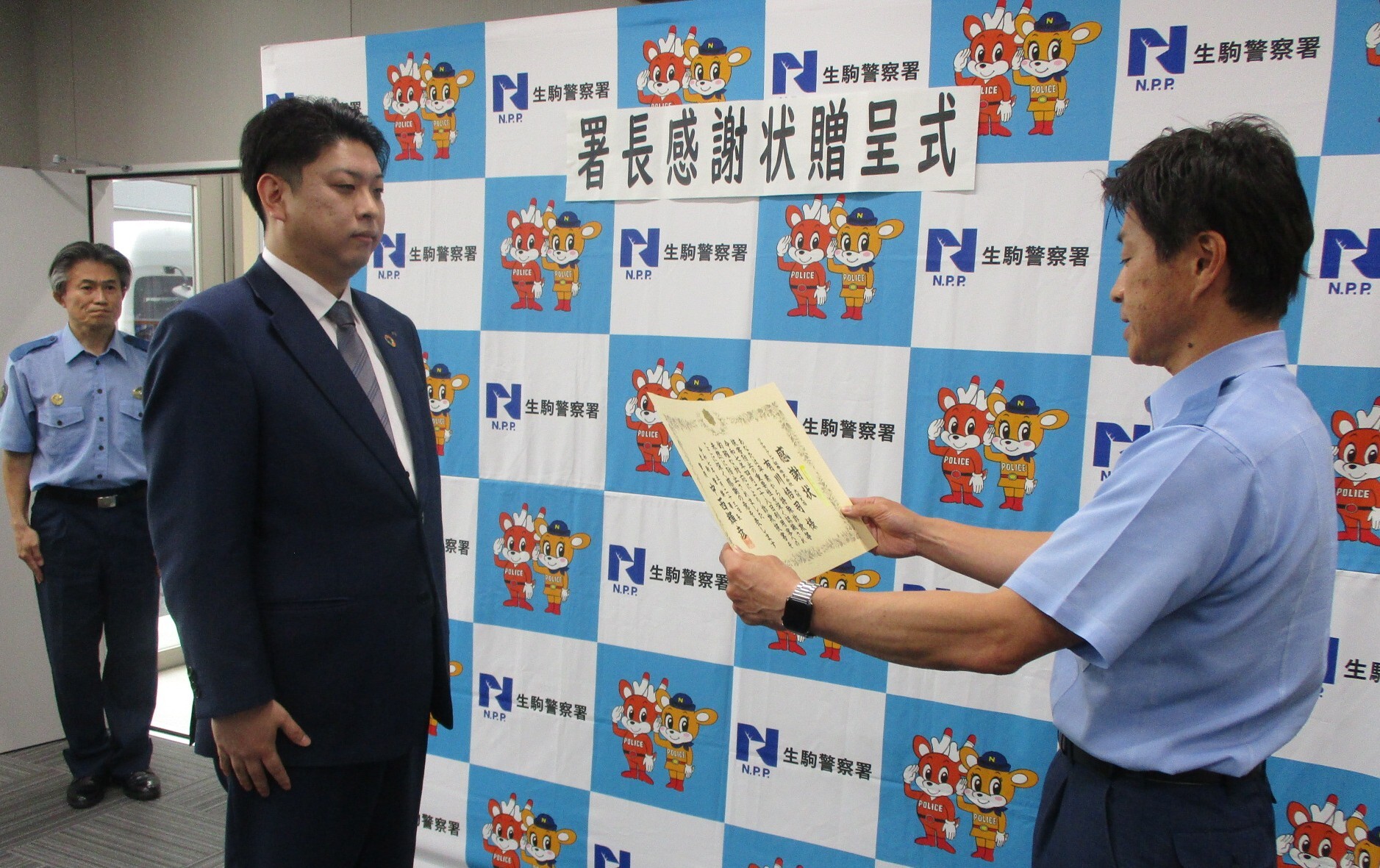 有川様が生駒警察署長から感謝状を読み上げている様子