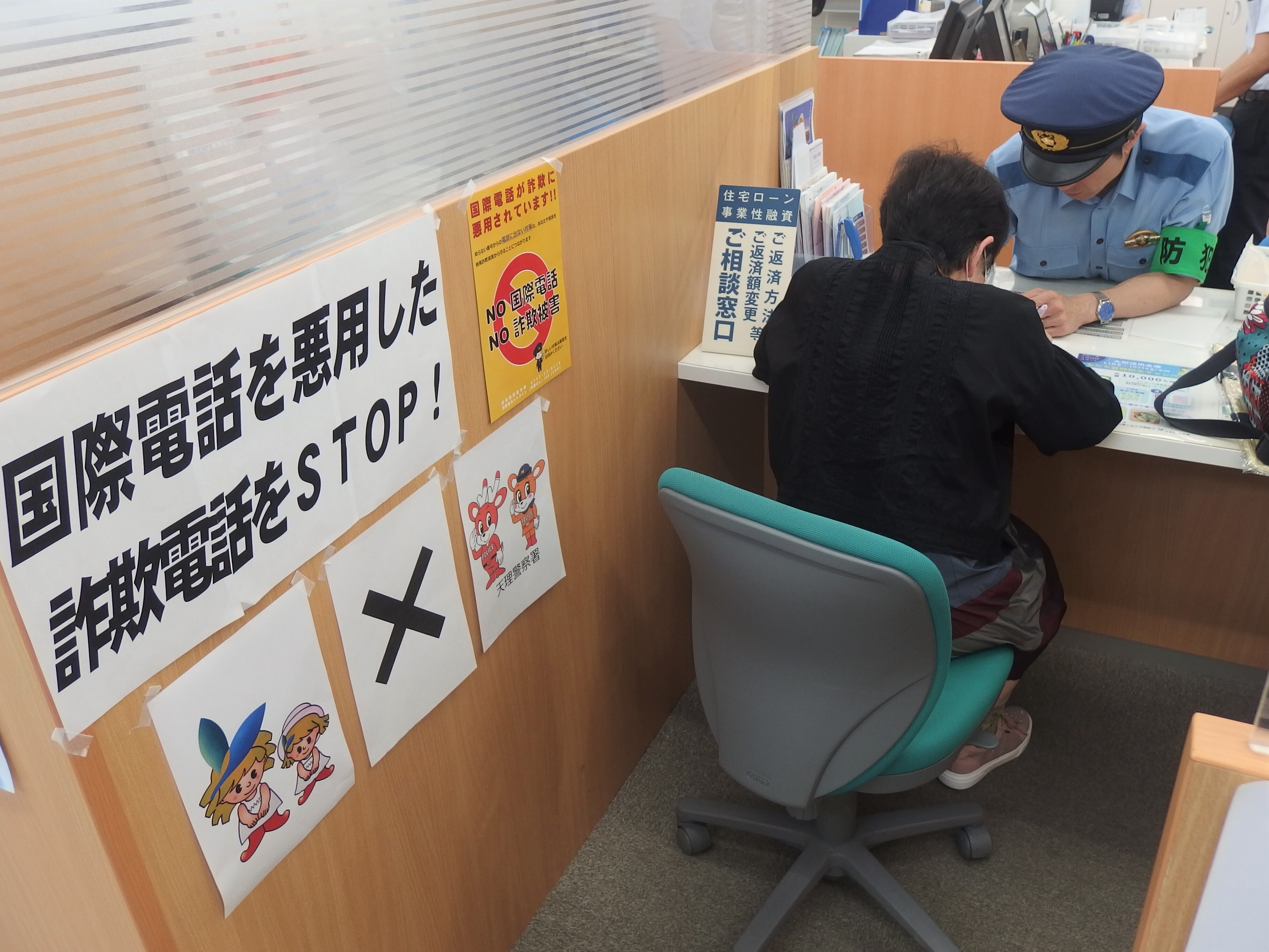 窓口で警察官が詐欺電話に退位する注意喚起の説明をしている様子