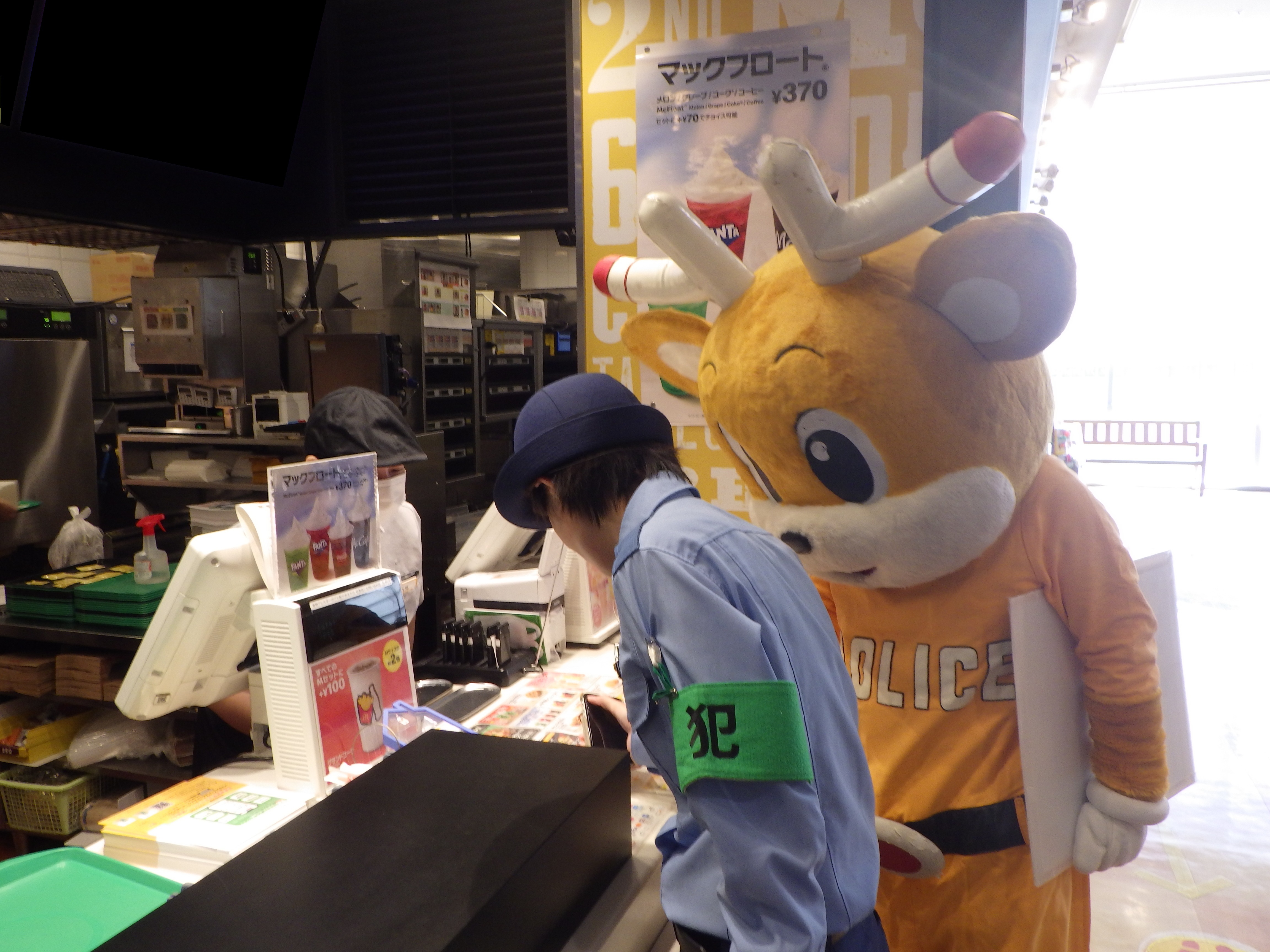 警察官とナポくんがマクドナルドのカウンターに立っている様子