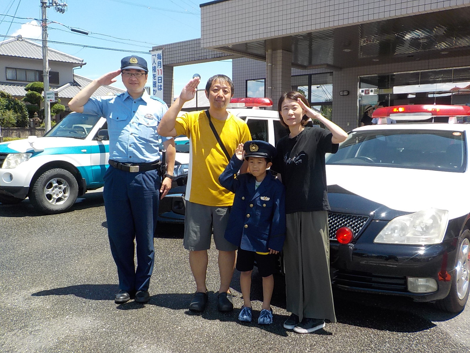 警察官とパトカーと並び写真をとる家族