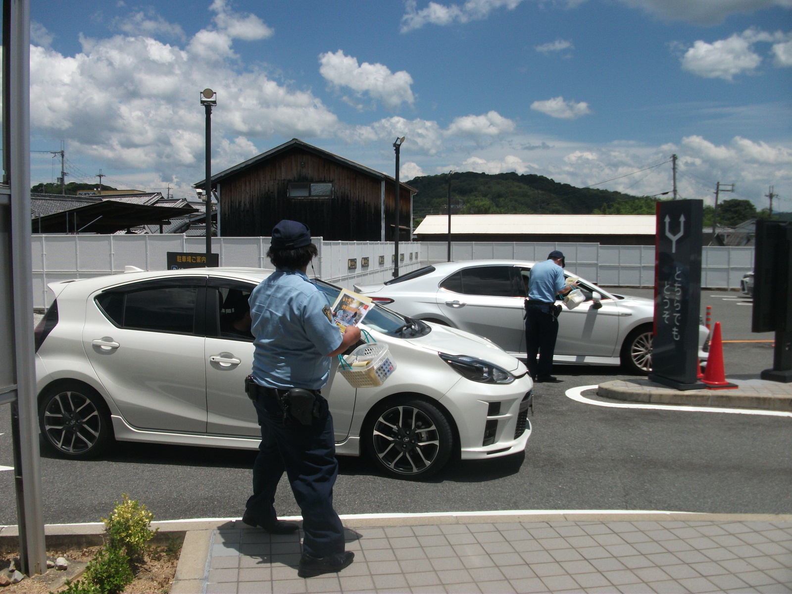 ドライブスルー利用者に対し、警察官がナポリス登録推奨チラシを配布し説明する様子