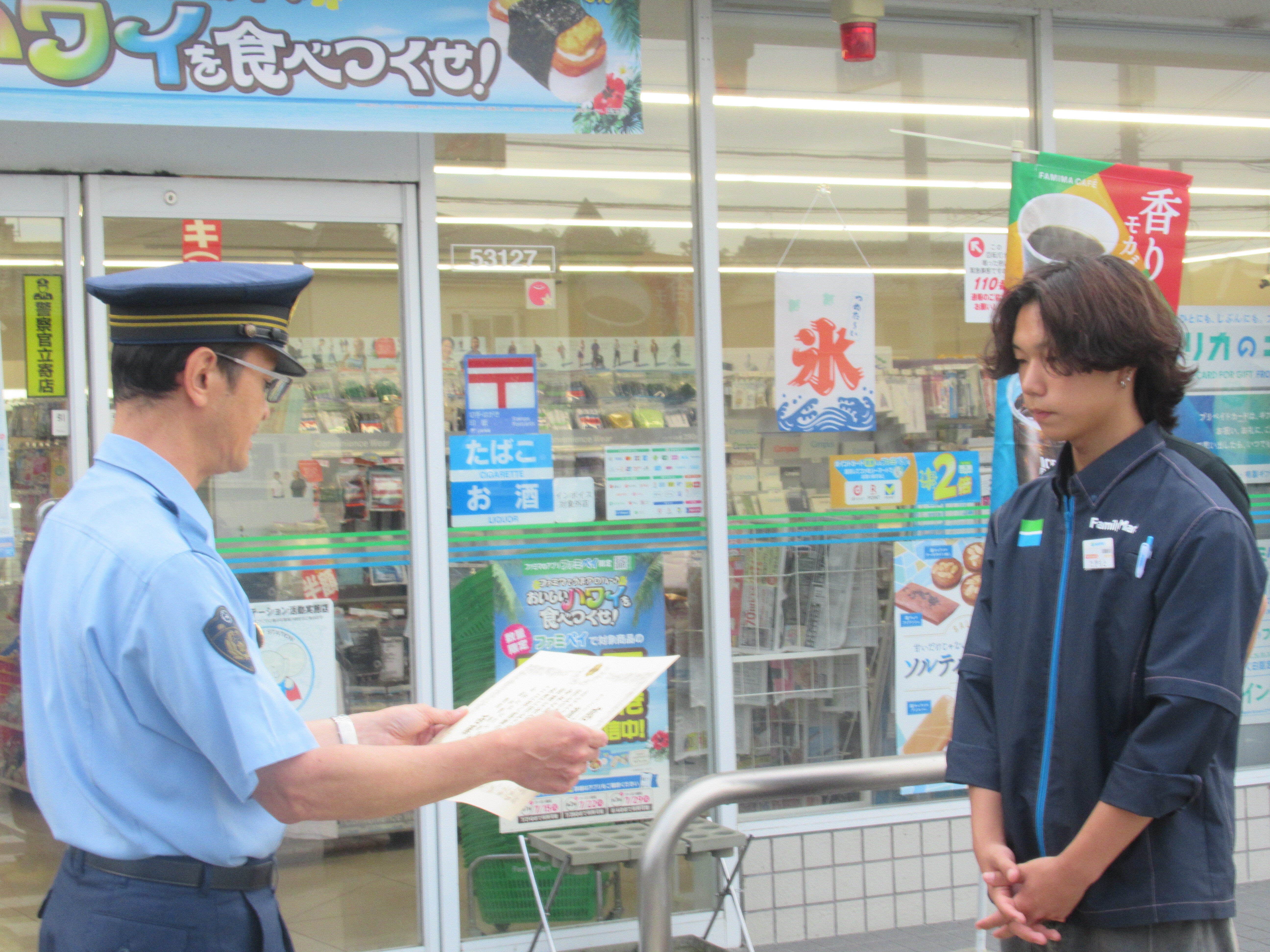 コンビニエンスストアの前で賞状を読み上げている様子2