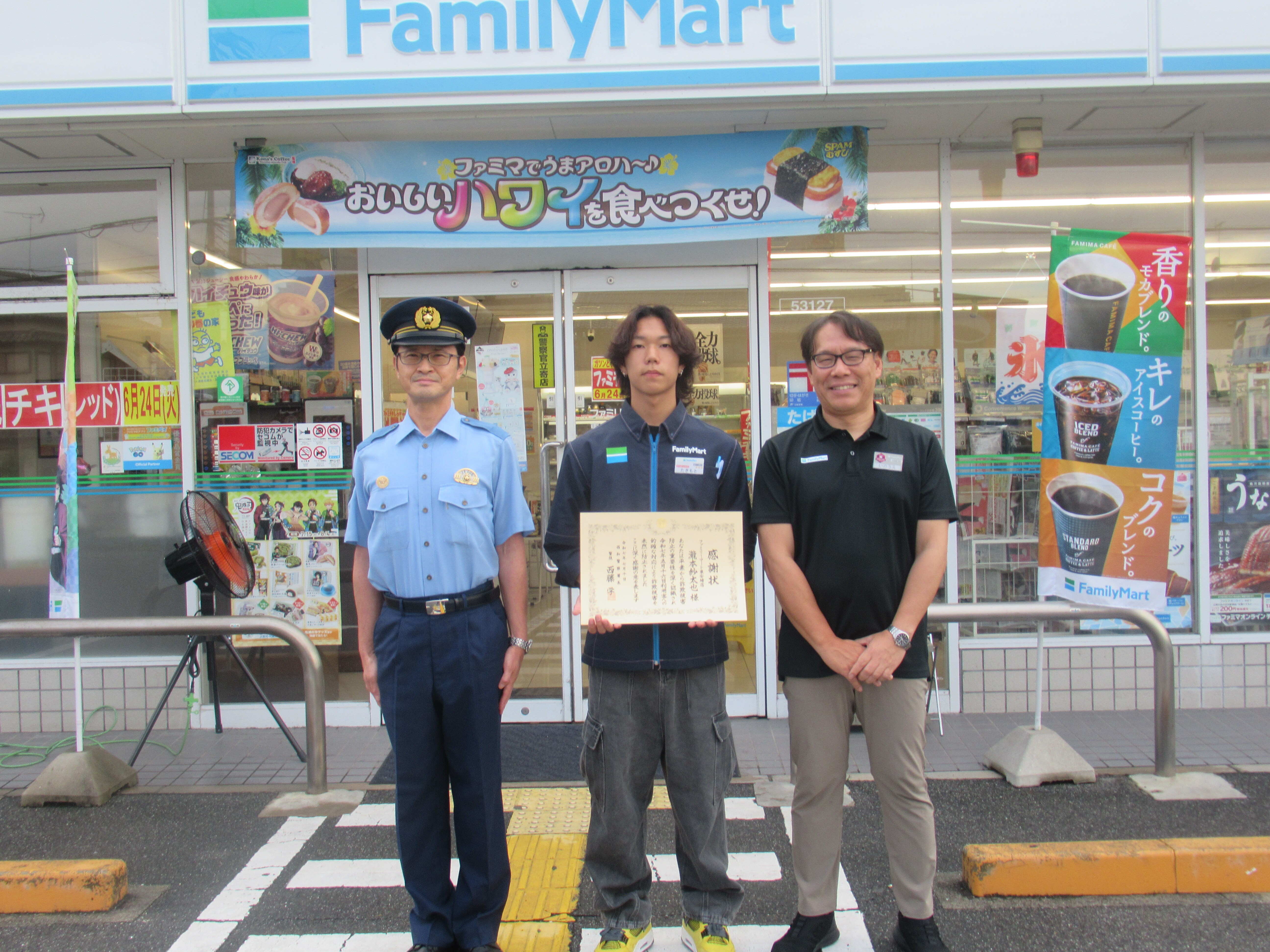 コンビニエンスストアの前で賞状を持って並んでいる様子