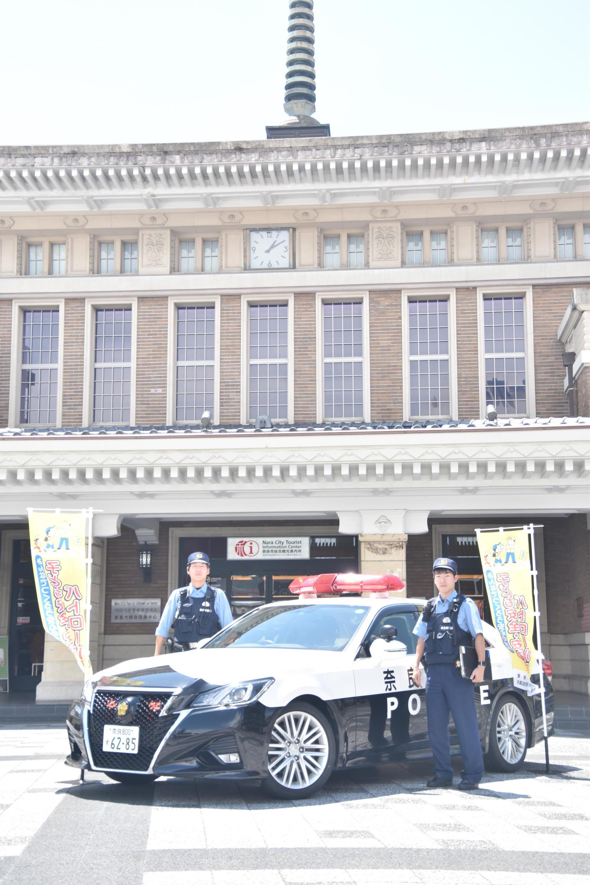 警察官がパトカーとともに写真を撮る様子
