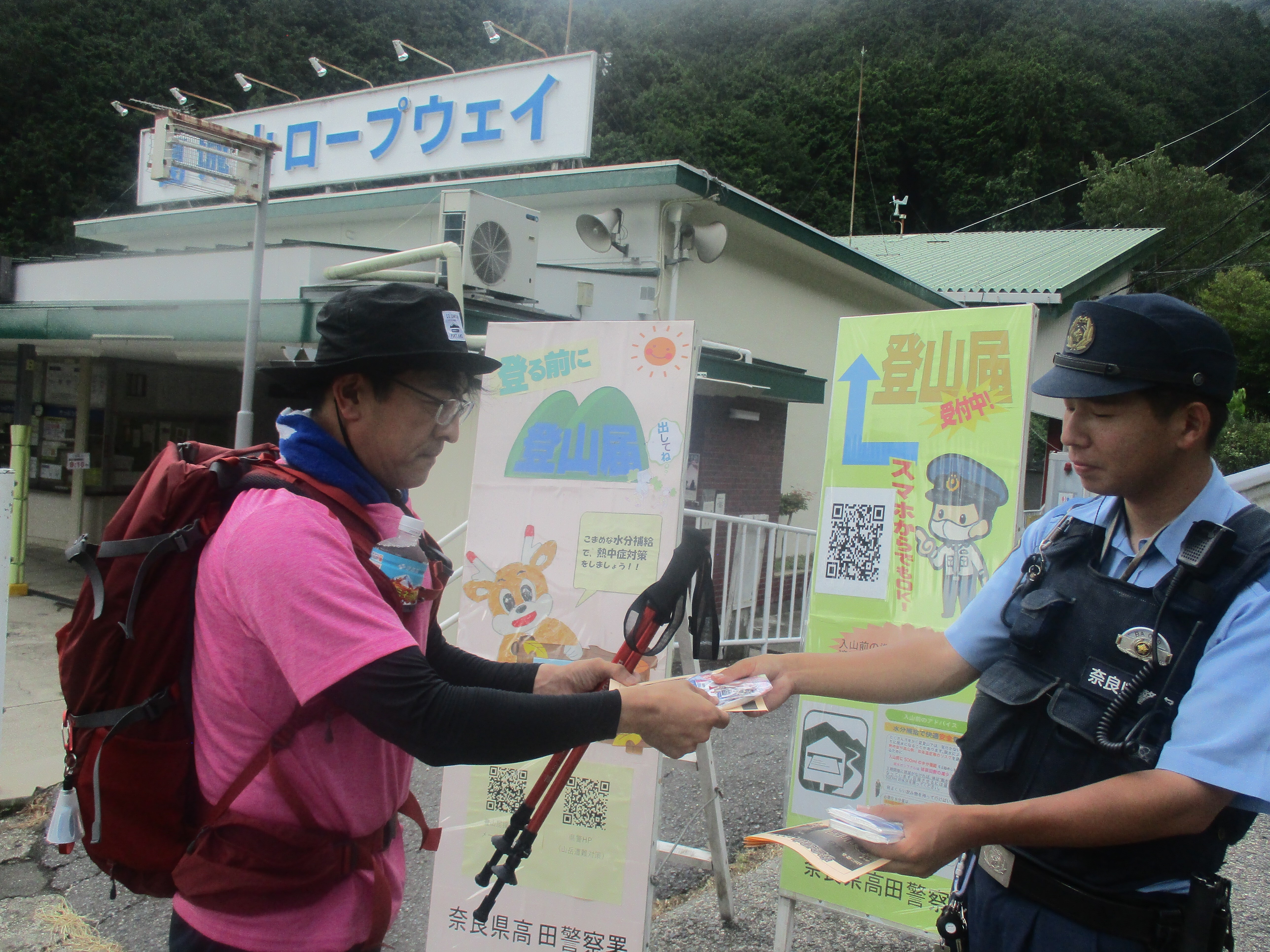 登山者に警察官が登山届提出のお願いをしている様子