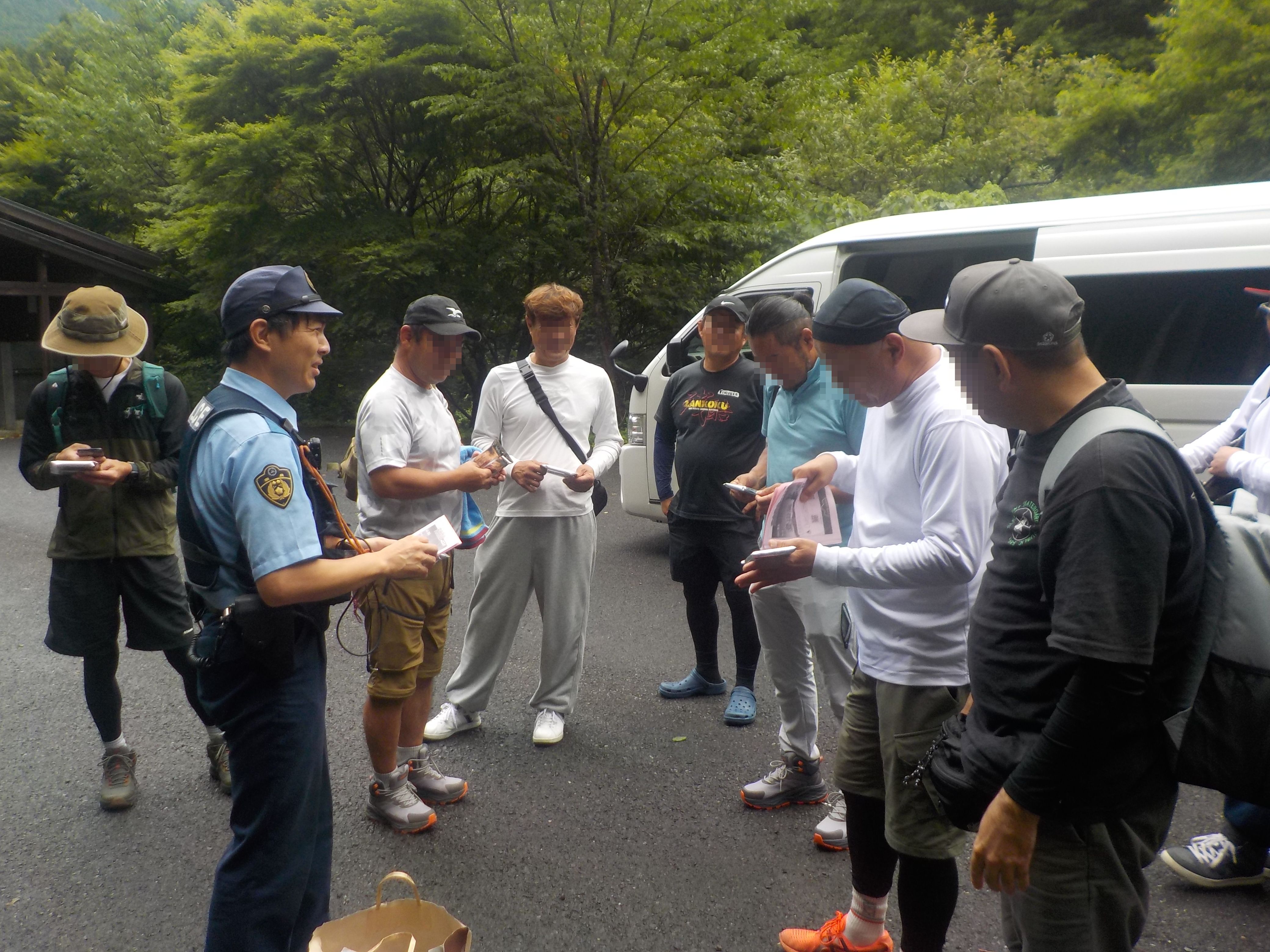 警察官が登山客へ啓発チラシを配布している様子