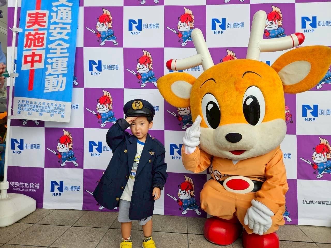 子供が警察の制服を着てナポくんと記念撮影