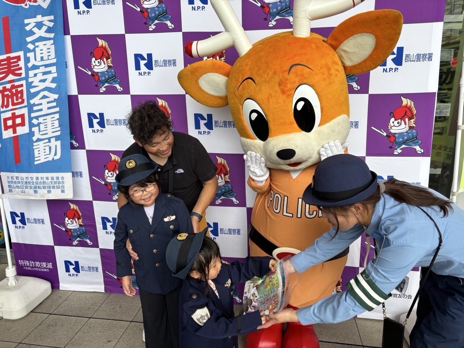 警察官が警察の制服を着た子供に品物を渡している様子