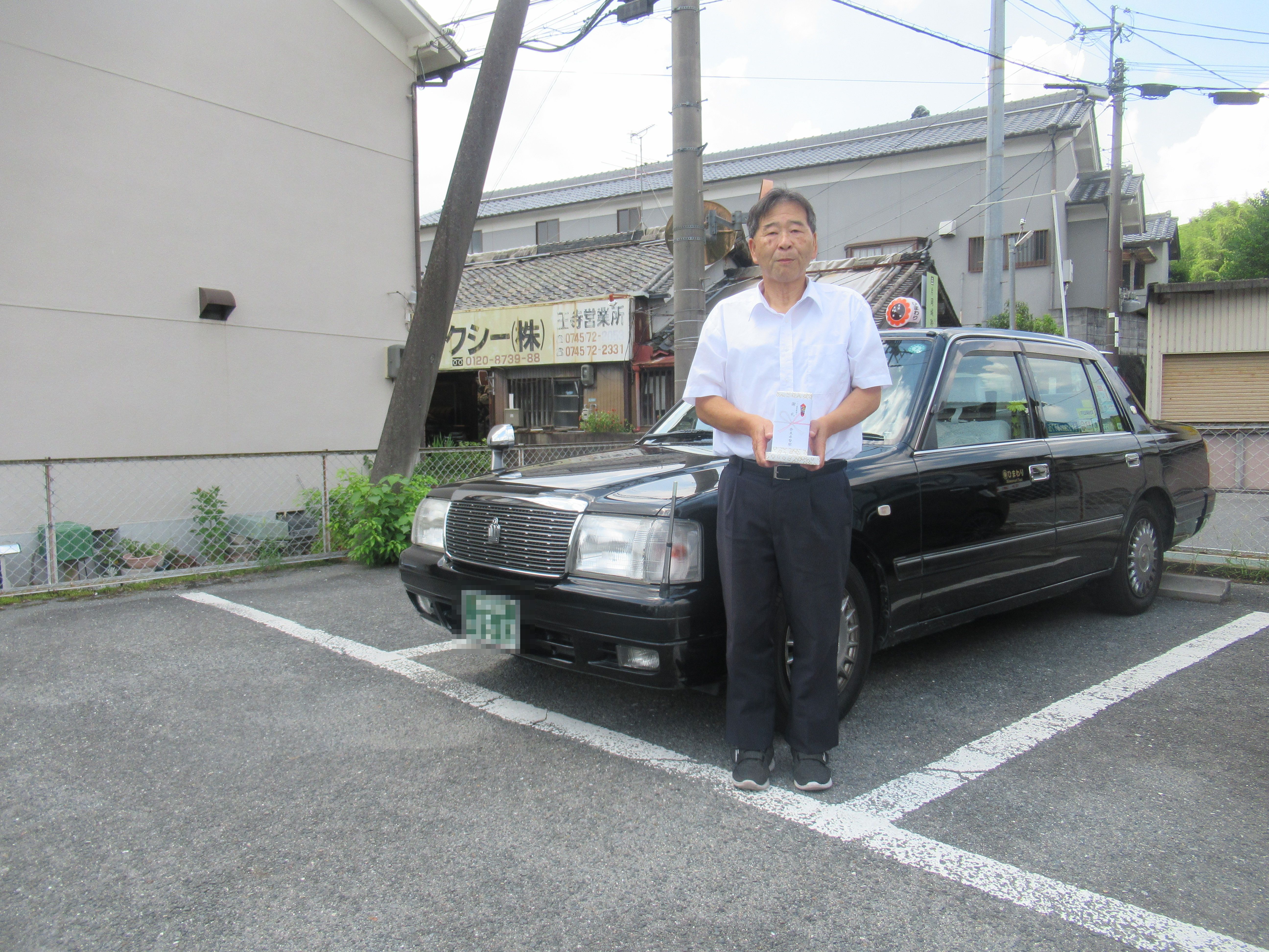 車の前で記念品を持っている様子