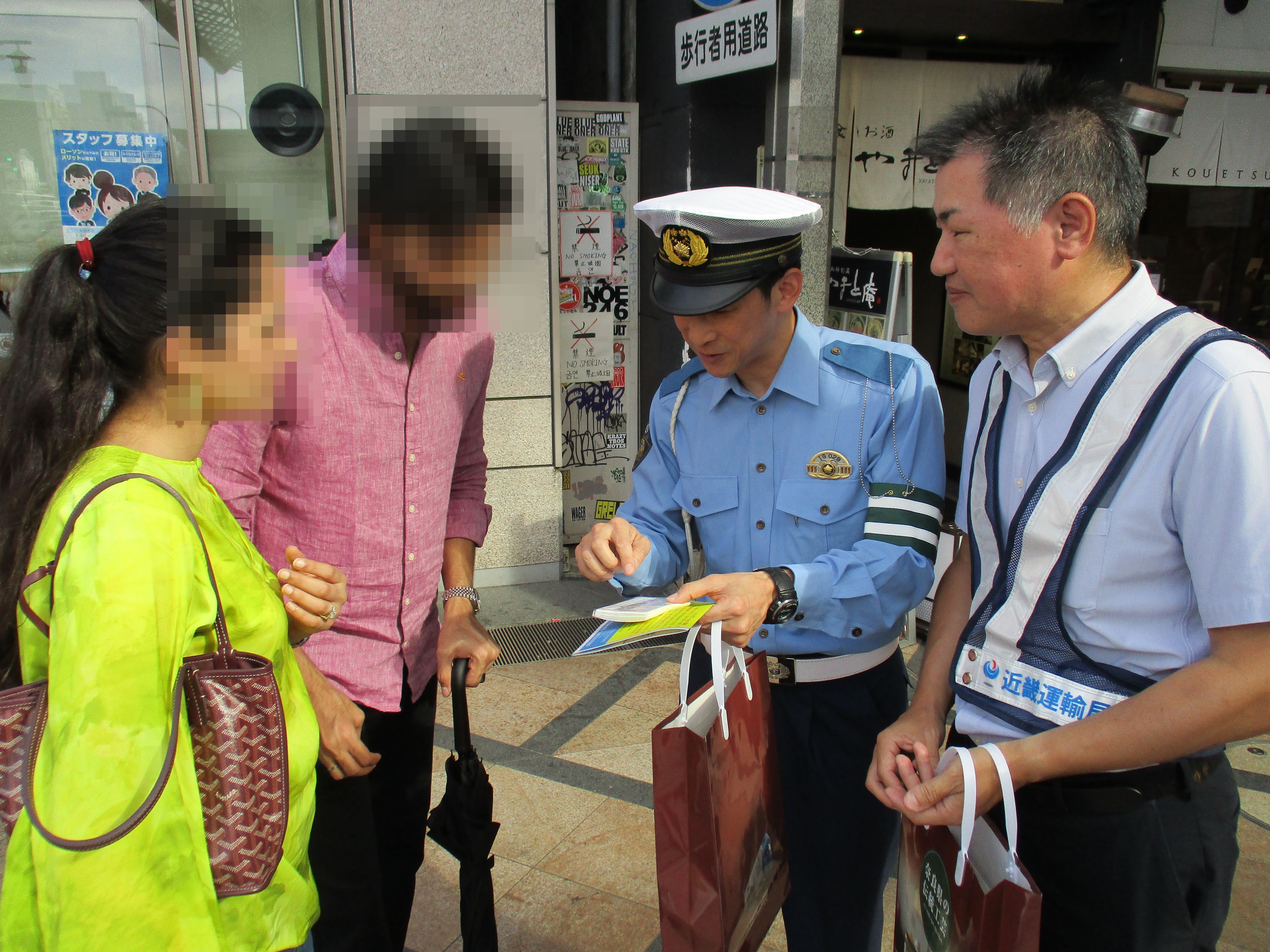 街中で外国の人に対して警察官が白タク啓発活動を行っている様子
