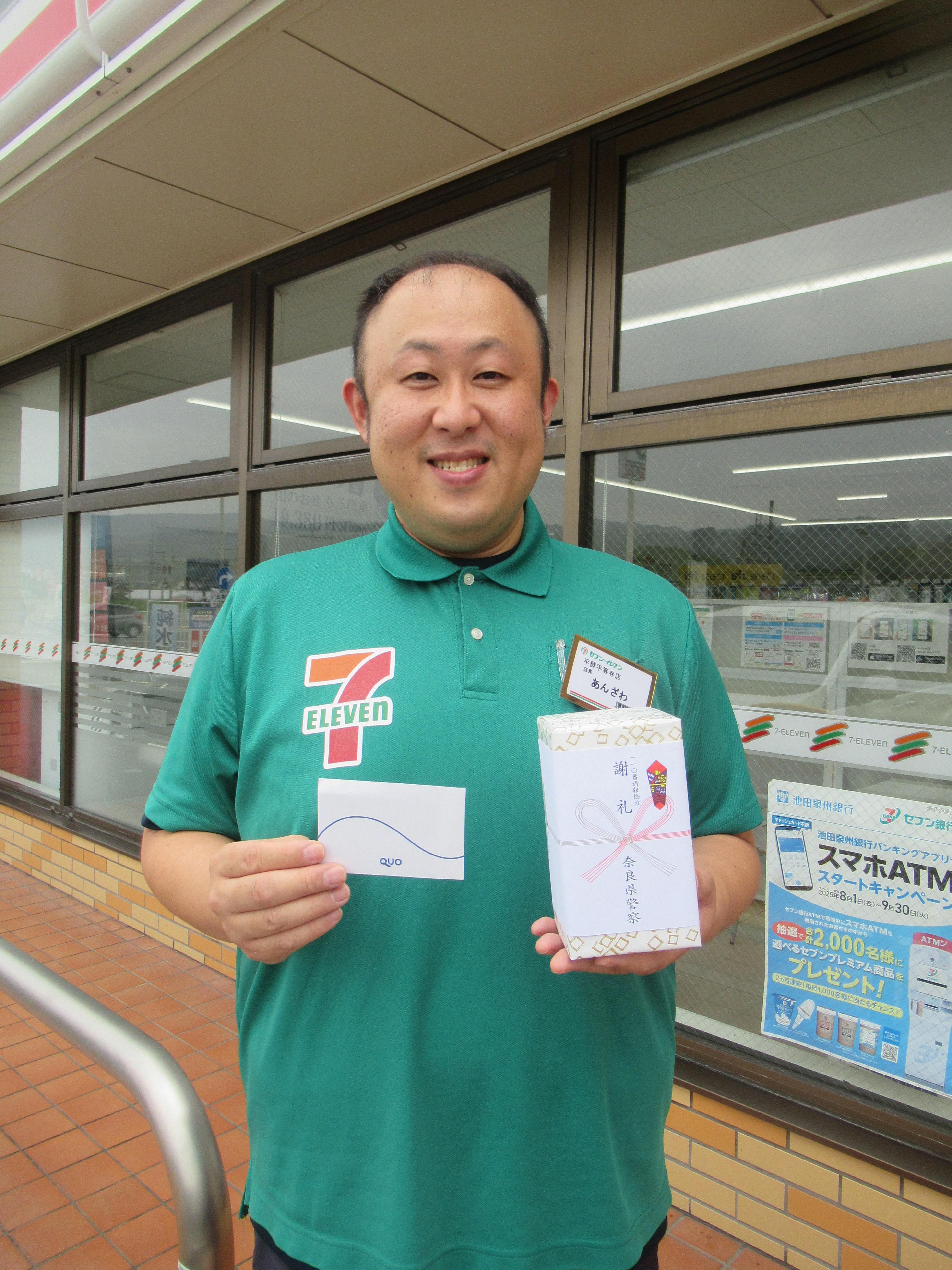 コンビニエンスストア店長が謝礼品を持って立っている様子2