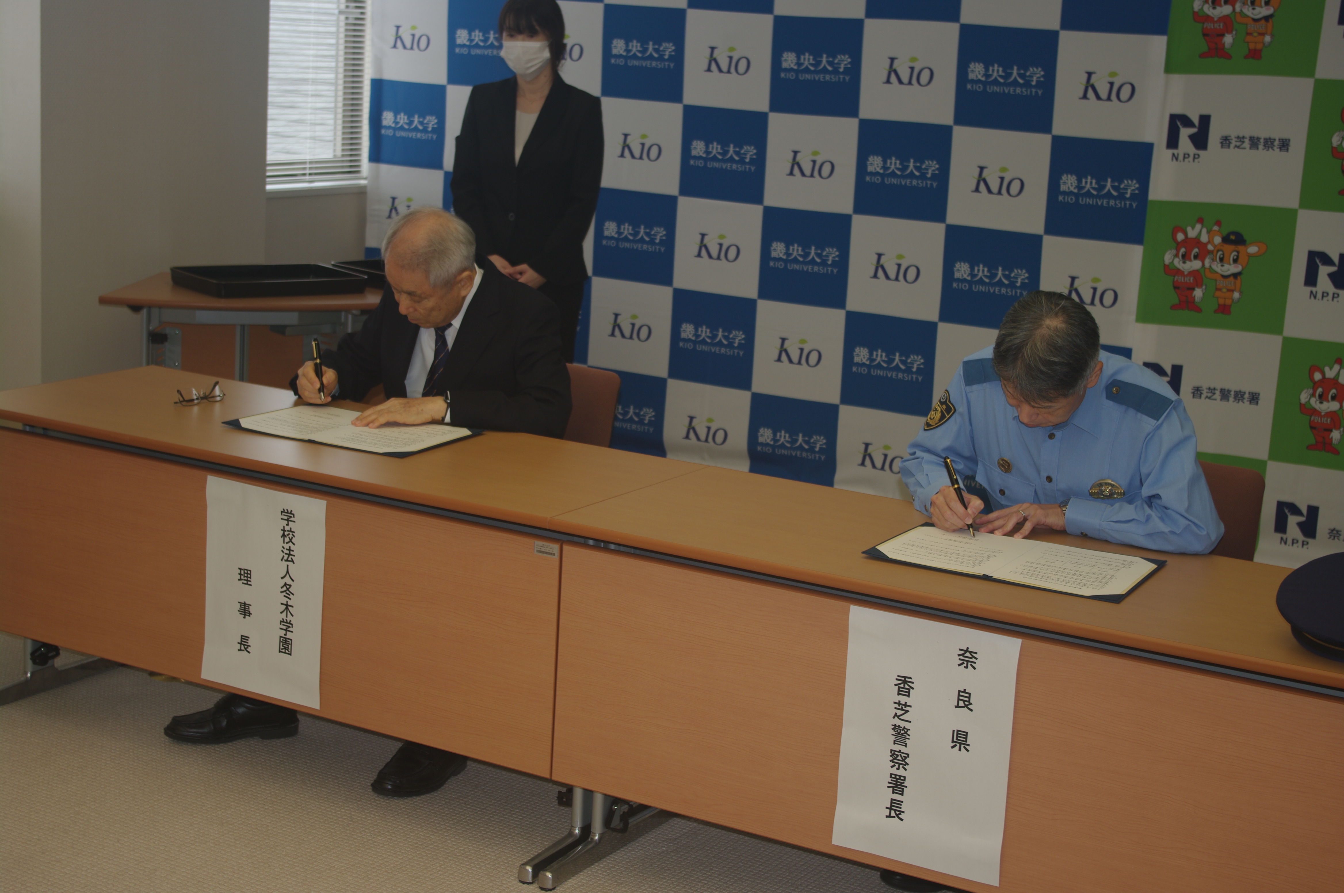 冬木学園理事長と香芝署長がサインをしている様子