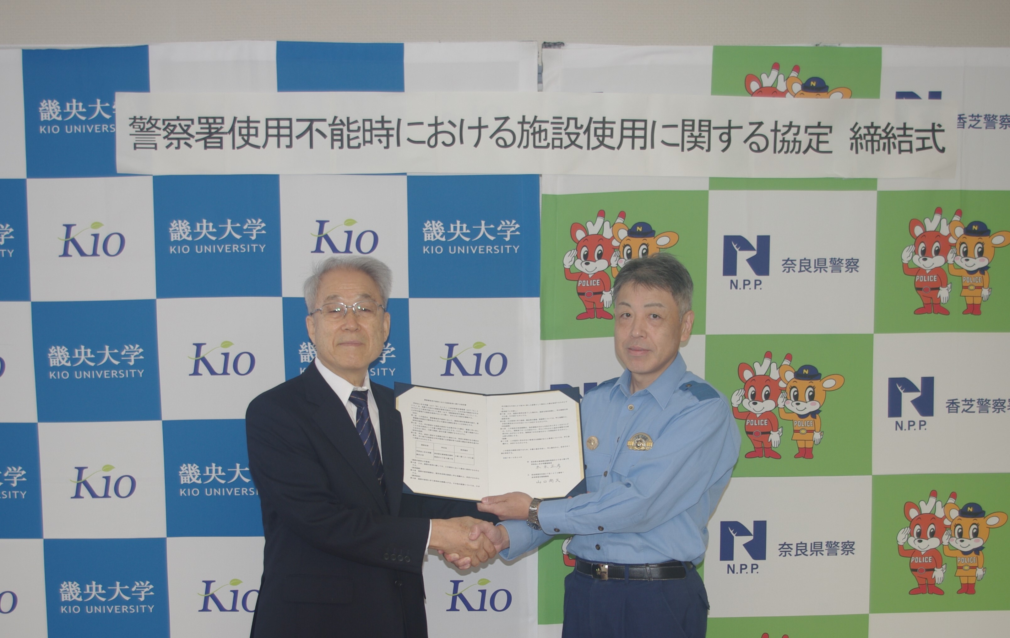 学園理事長と香芝署長が握手している様子