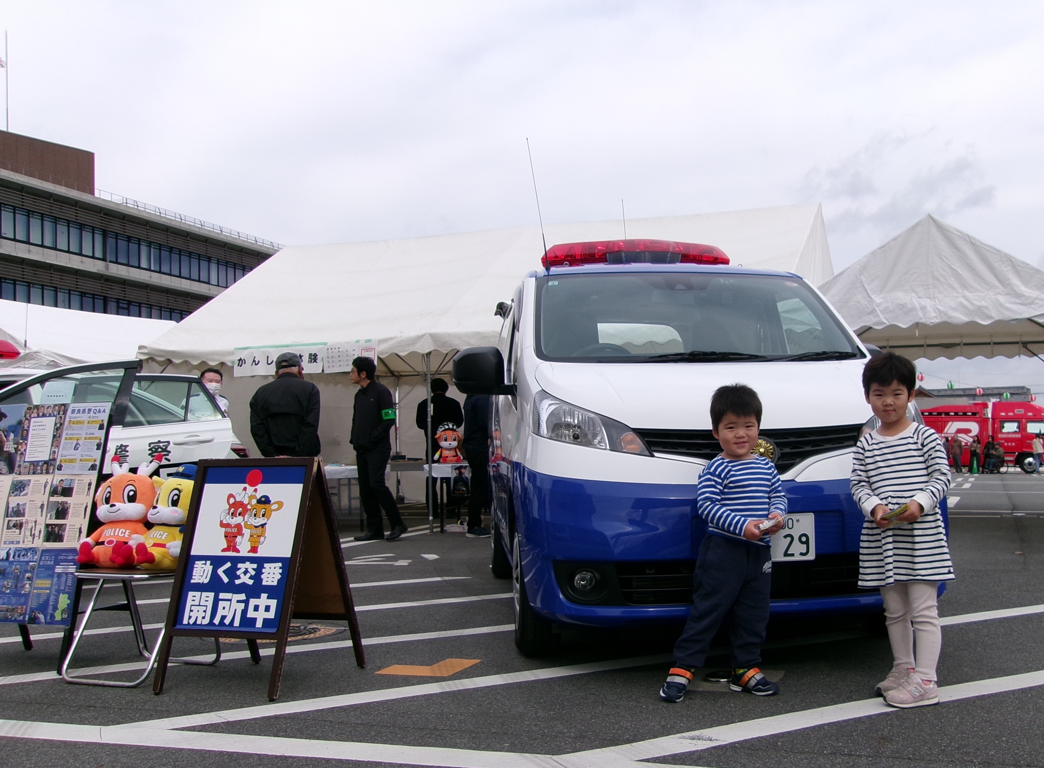 子供が動く交番パトカーの前に立っている様子
