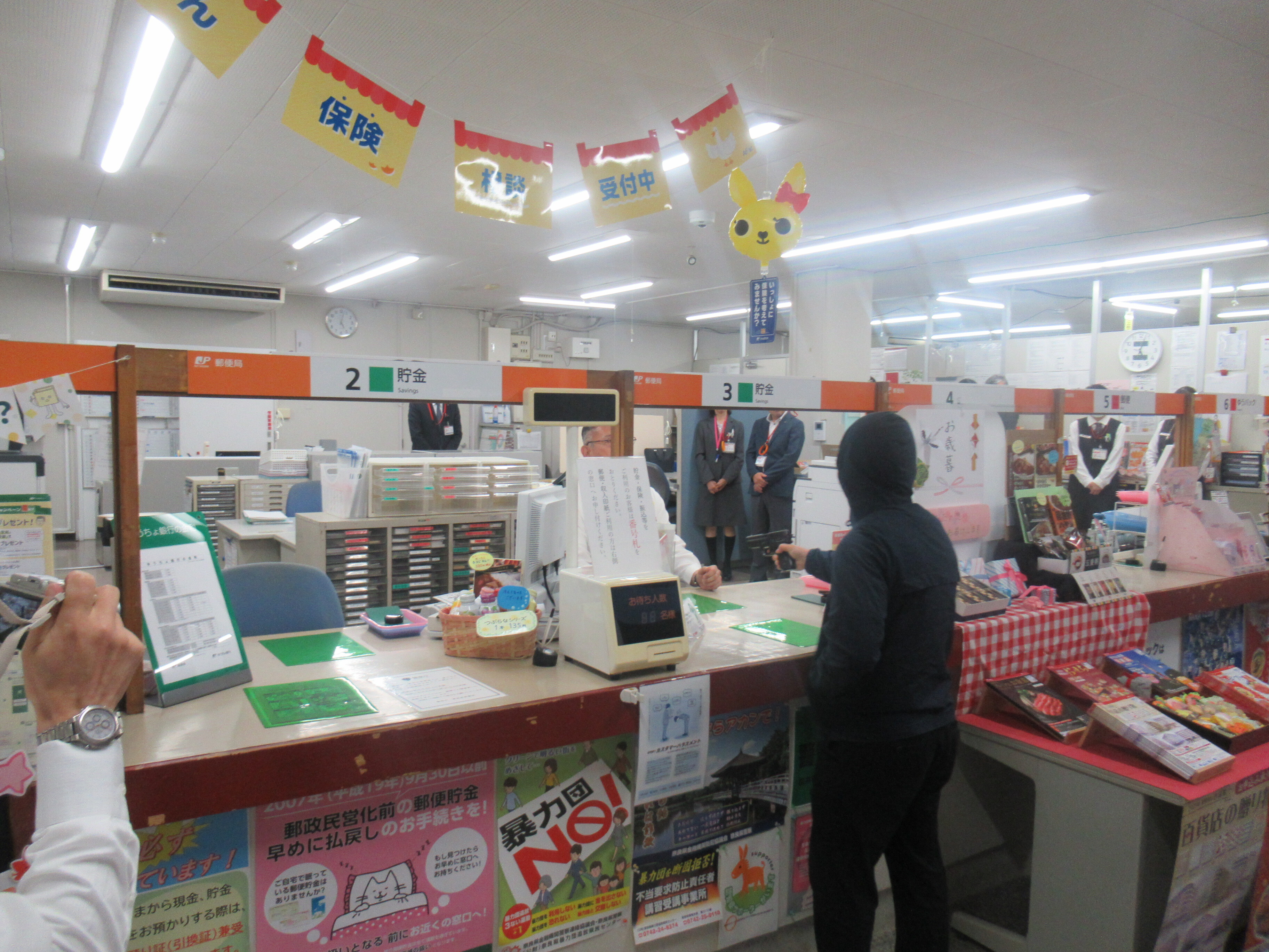 強盗犯役が郵便局員を脅している様子1