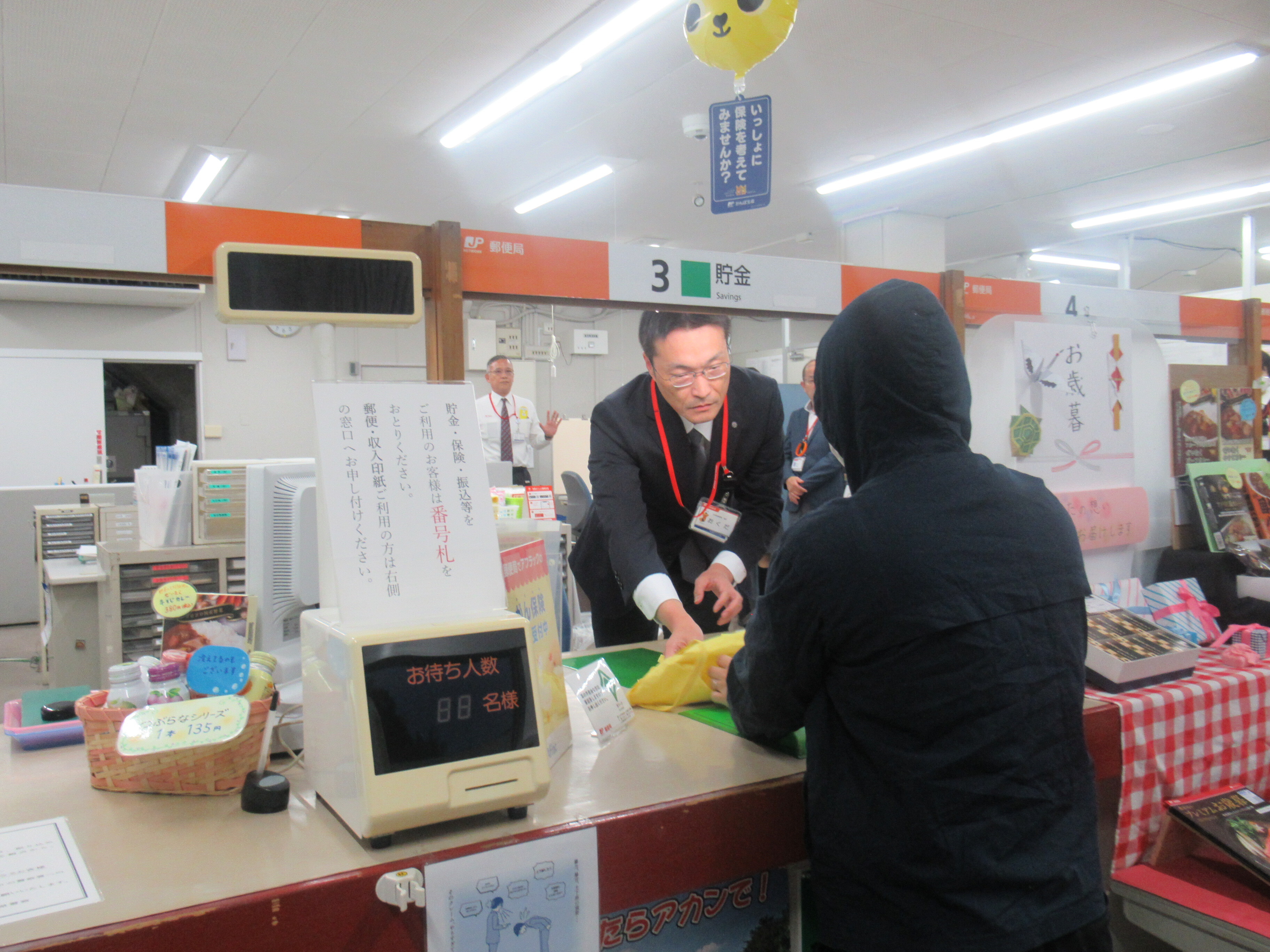 郵便局員が犯人役に袋を手渡している様子