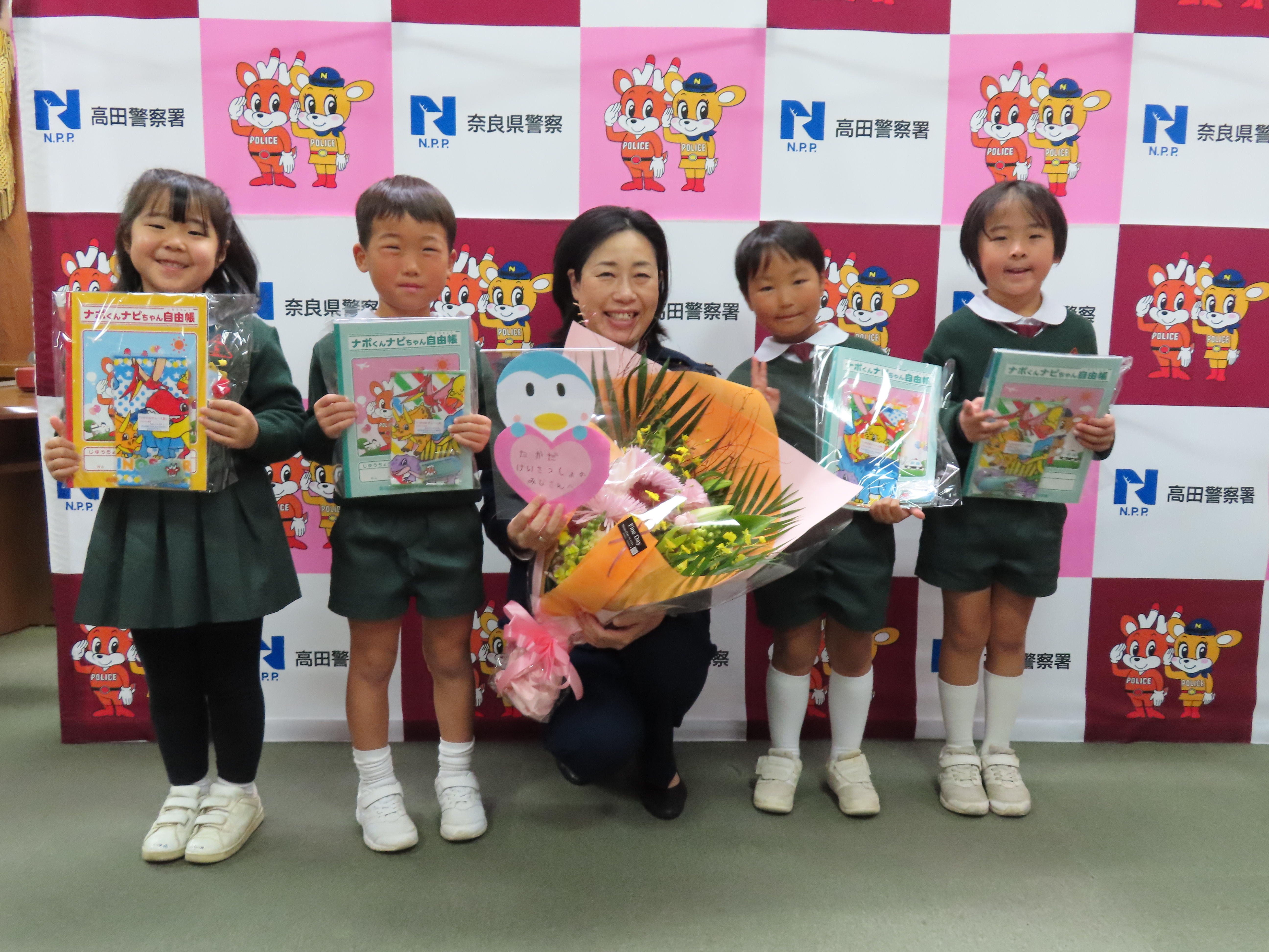 園児達と高田署長が花束などを持って並んでいる様子