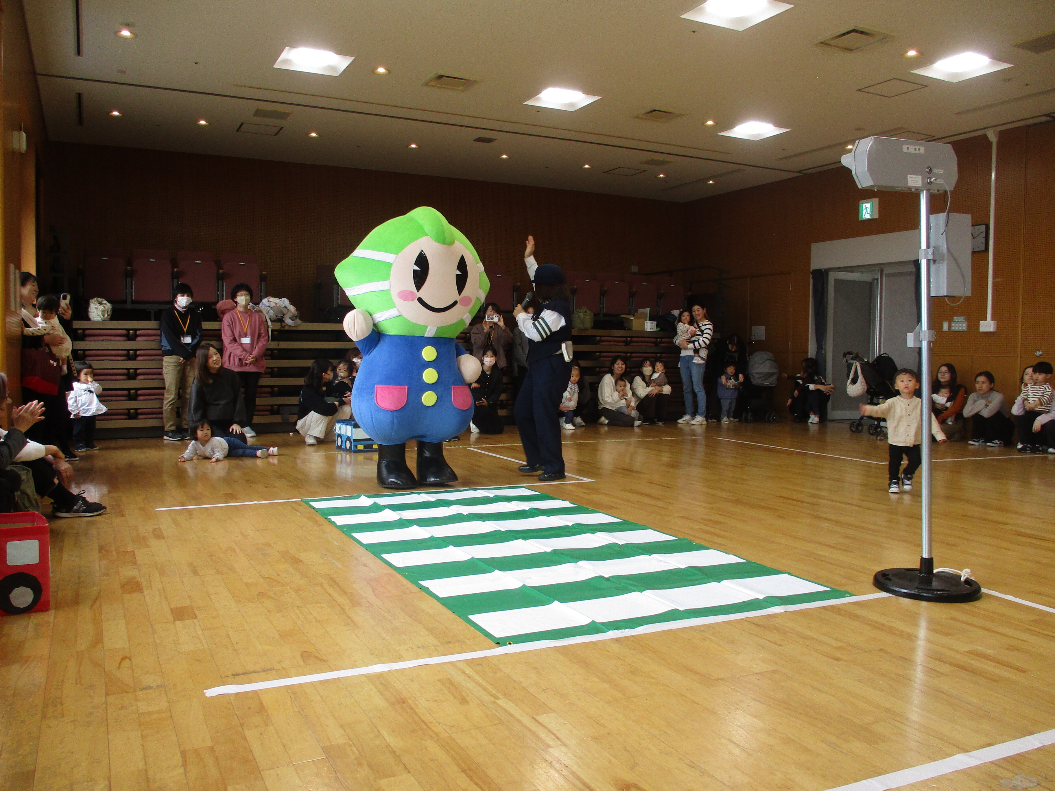 子ども達がマスコットキャラクター「カッシーくん」と横断歩道を渡っている様子