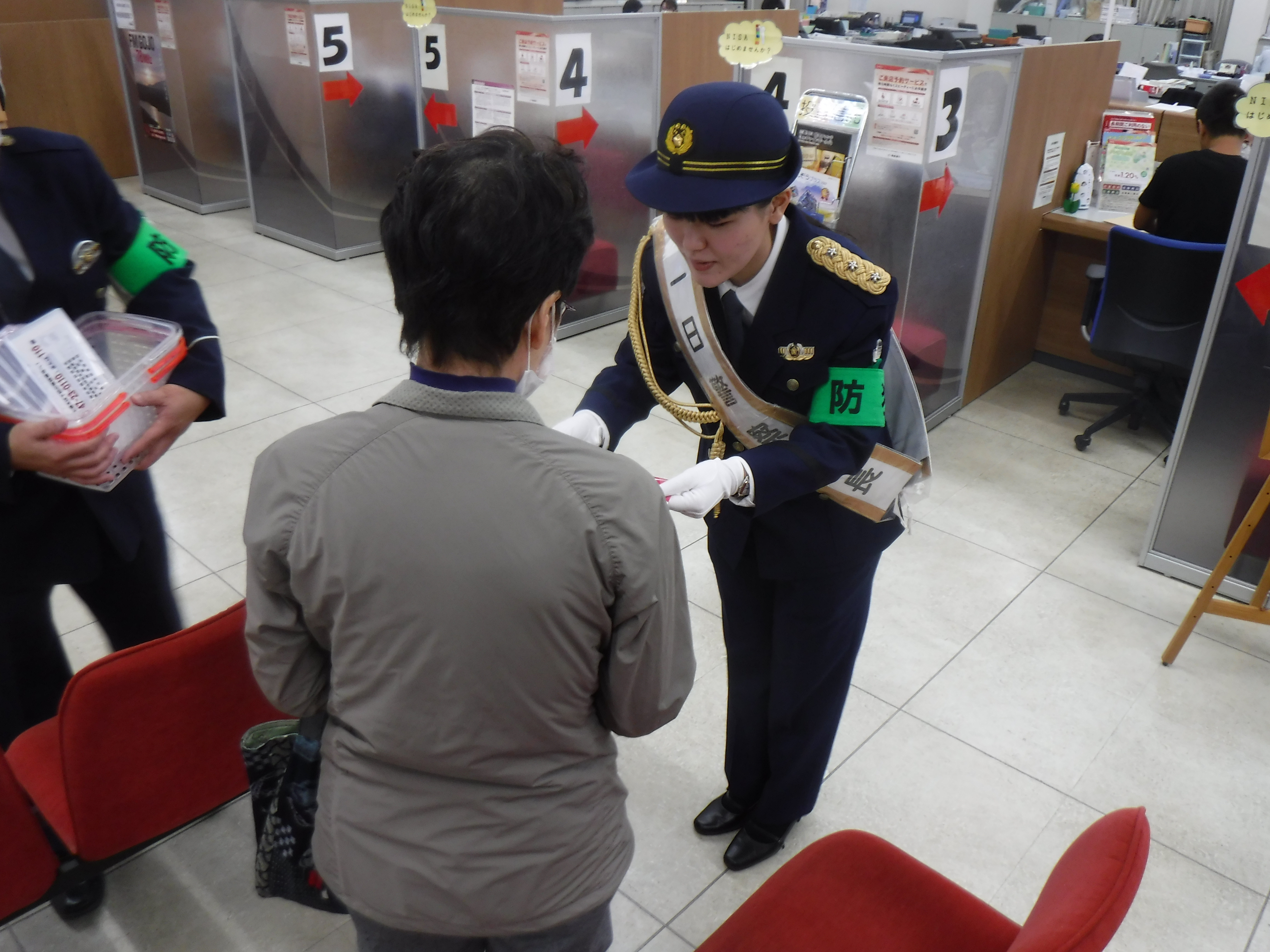 五條署一日署長が特殊詐欺啓発防止通帳ケースを配布している様子