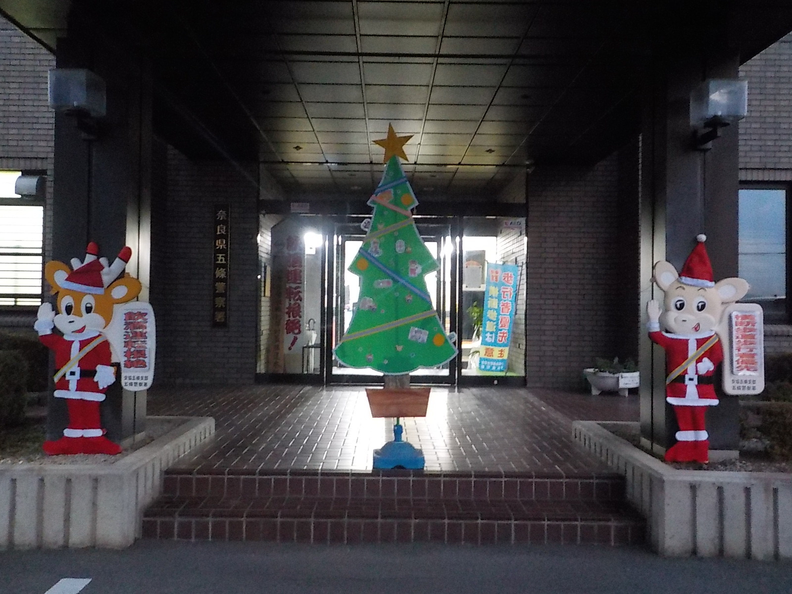 五條署の入り口でサンタナポくん、ナピちゃん、クリスマスツリーが飾られている様子